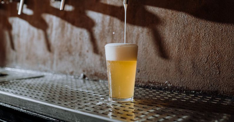 Craft Beer Bars - Beer Pouring Into Clear Drinking Glass on Metal Surface