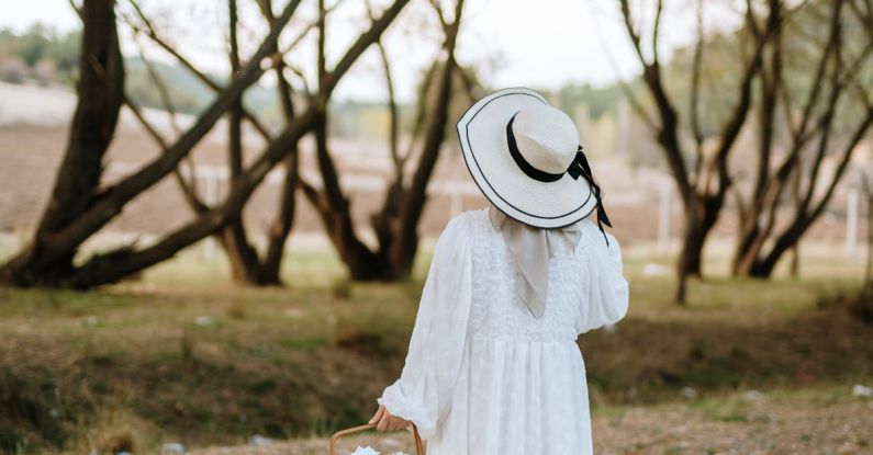 Picnic Spots - A woman in a white dress and hat is walking through the woods