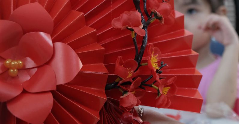 Art Festivals - A person holding a red paper fan with red flowers