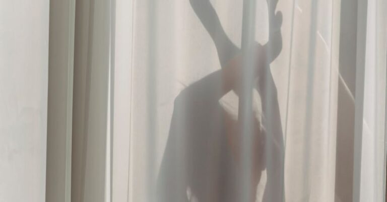 Dance Performances - Shadow of anonymous female dancer performing sensual movements behind translucent white curtains in sunlight